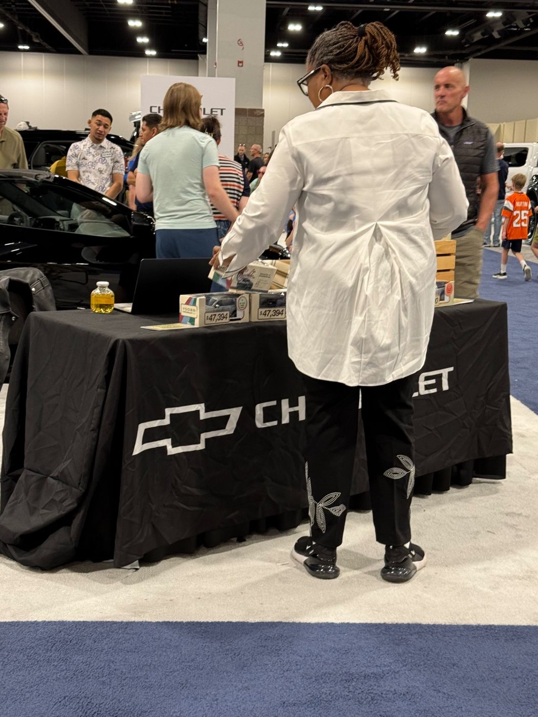 Foot traffic moving past the Motibox table at the Colorado Auto Show